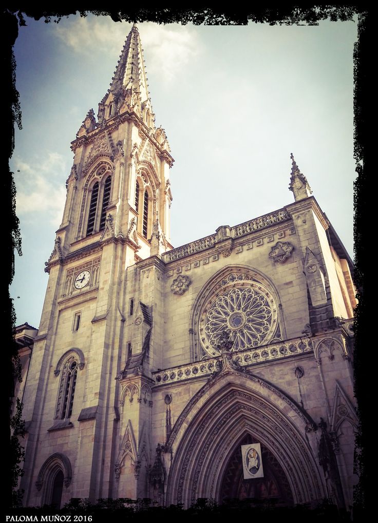 an old cathedral with a clock on it's side and sky in the background