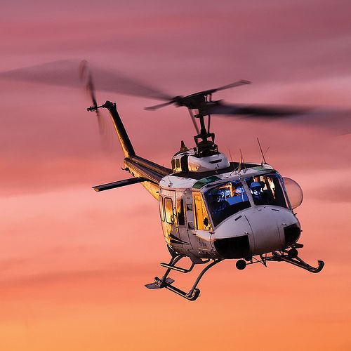 a helicopter flying in the air at sunset