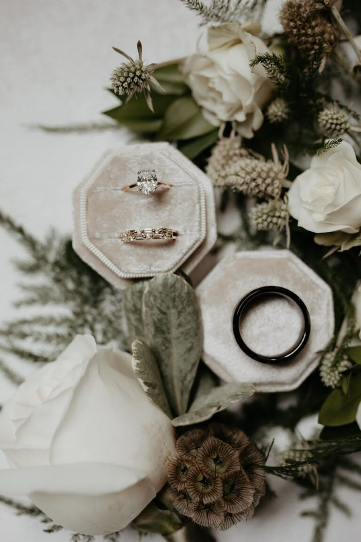 two wedding rings sitting on top of flowers