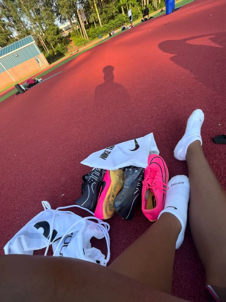 a person sitting on the ground with their feet propped up next to bags and tennis racquets