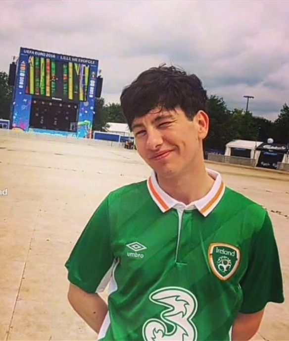 a young man wearing a green and white soccer jersey