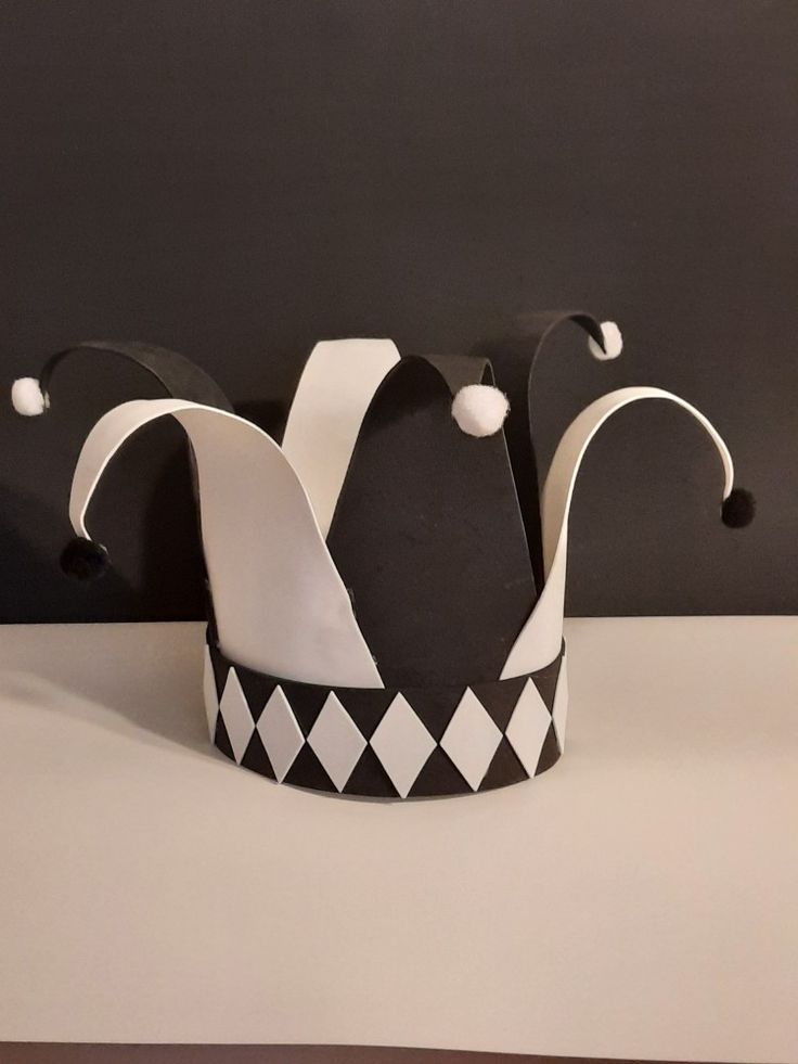 a black and white crown sitting on top of a table next to a gray wall