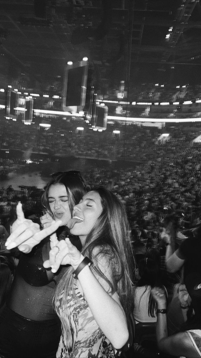 two young women sharing a piece of food in front of an audience at a concert