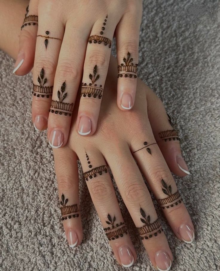 two hands with henna tattoos on their fingers