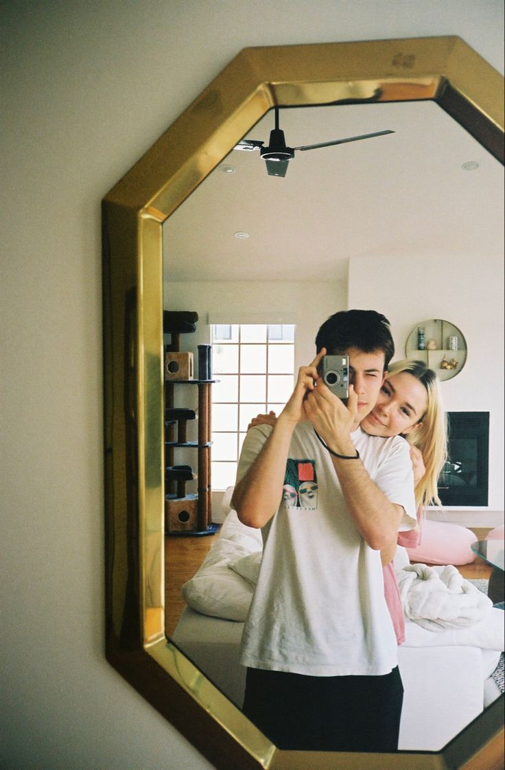 a man and woman taking a selfie in front of a mirror