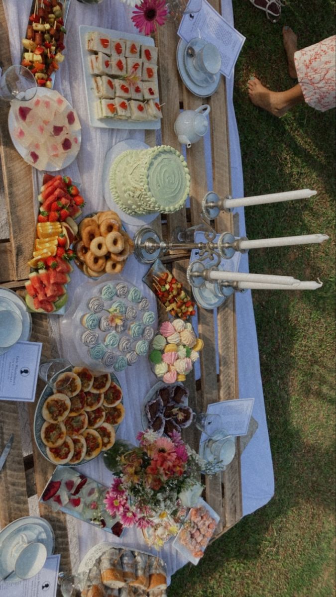 an outdoor picnic with food and drinks on the table, ready to be served for guests