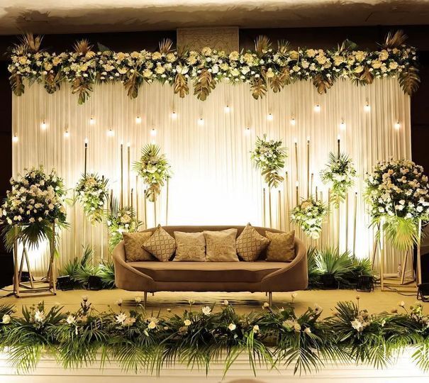 a couch sitting on top of a lush green field covered in flowers and greenery