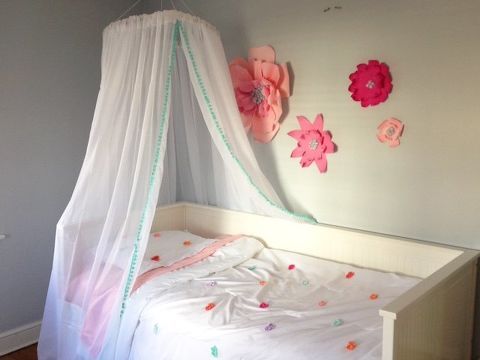 a white bed with pink flowers on the headboard and canopy over it in a bedroom