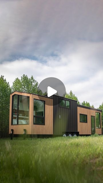 a tiny house on wheels sits in the middle of a grassy field with trees around it