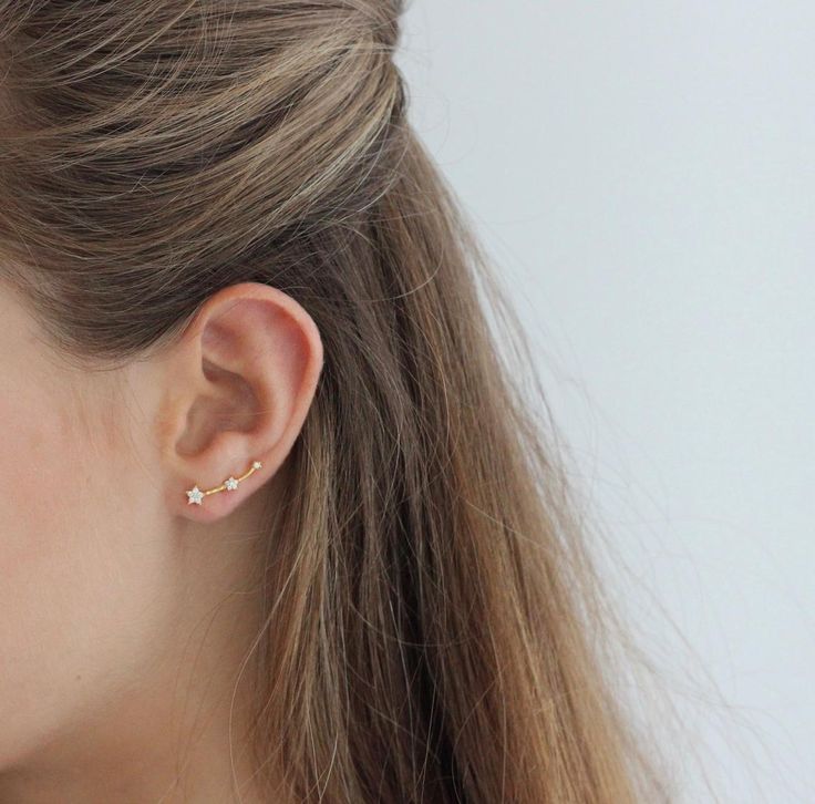 a close up of a woman's ear with small gold studs on it