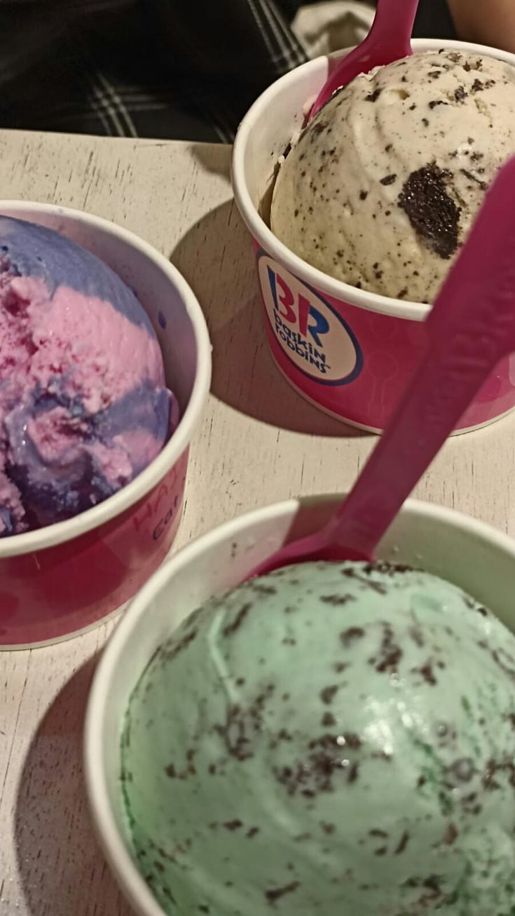 three ice creams in bowls on a table