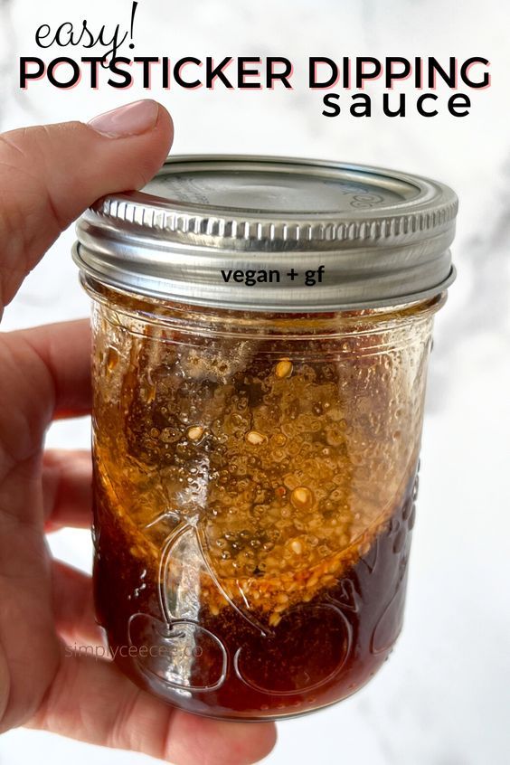 a hand holding a mason jar filled with vegan and gf sauce on a white background