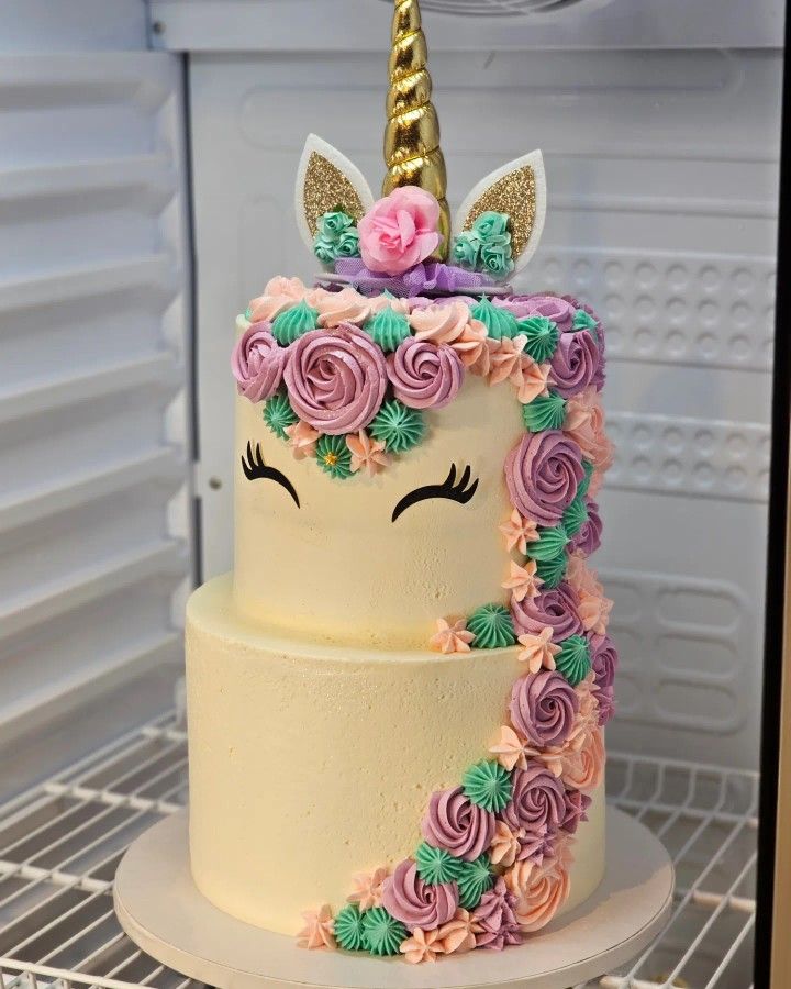 a cake decorated with flowers and a unicorn's horn on top is sitting in the refrigerator