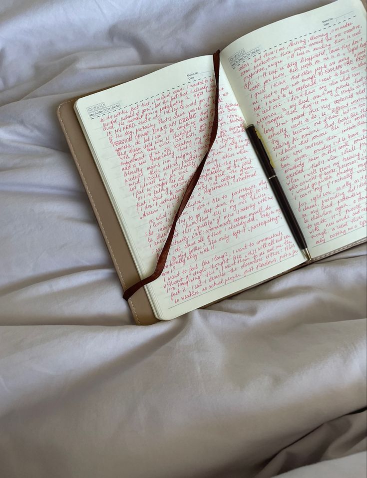 an open notebook with writing on it and a pen resting on the book's cover