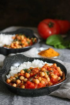 two black pans filled with rice and chickpeas on top of a table