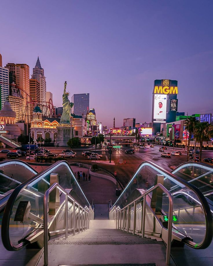 an escalator in front of a cityscape at night with neon lights