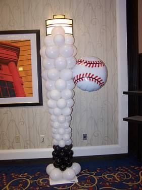 a balloon sculpture with a baseball on it in the middle of a room next to a wall