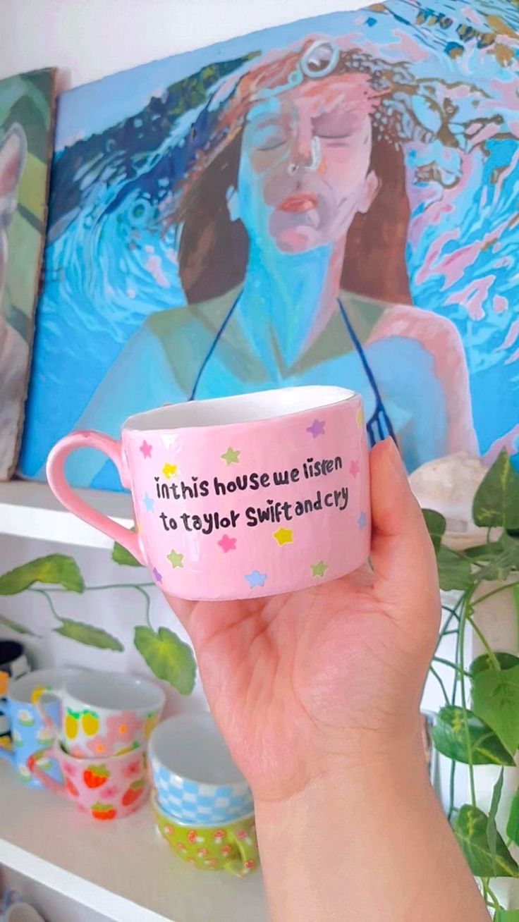 a hand holding a pink coffee cup with an image of a woman's face on it