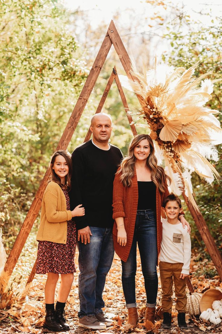 a family posing for a photo in front of a teepeel tent with leaves on the ground