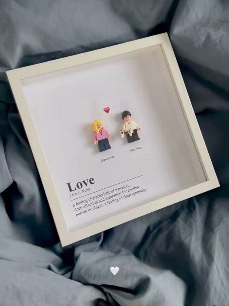 two small lego figures are in a shadow box