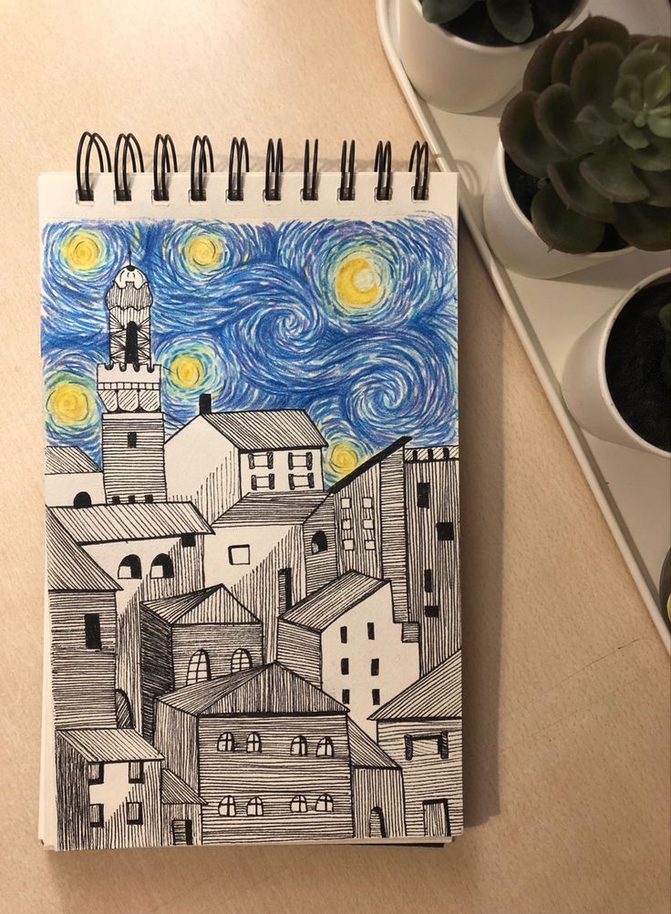 a spiral notebook with a drawing of a city at night and stars in the sky