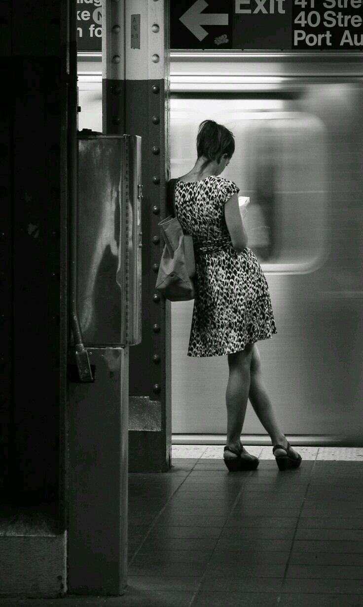 a woman in a short dress is waiting for the subway