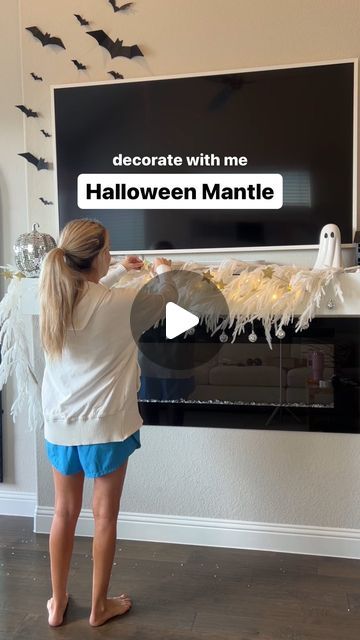 a woman standing in front of a flat screen tv with halloween decorations on the wall