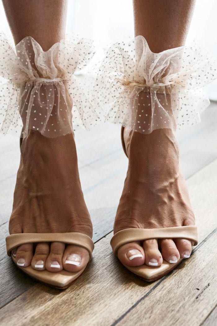 a woman's feet wearing high heels with bows on the toes and toenails