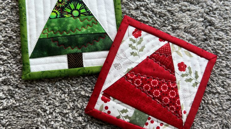 two quilted christmas trees sitting on top of a carpet next to each other, one green and the other red