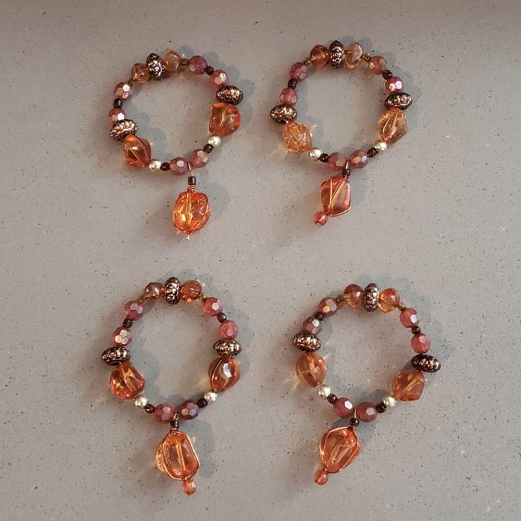 three bracelets with beads and charms on a table