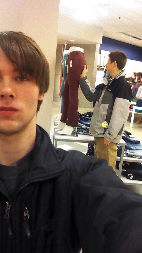 a young man is taking a selfie in front of some clothing mannequins