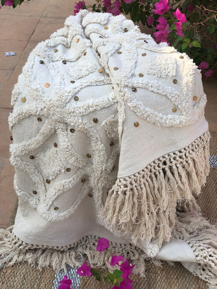 a white blanket sitting on top of a table next to purple flowers