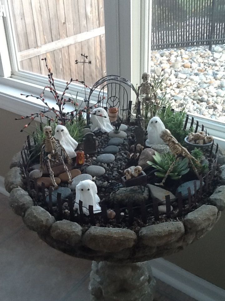 there are many halloween decorations in the bowl on the window sill with rocks and plants