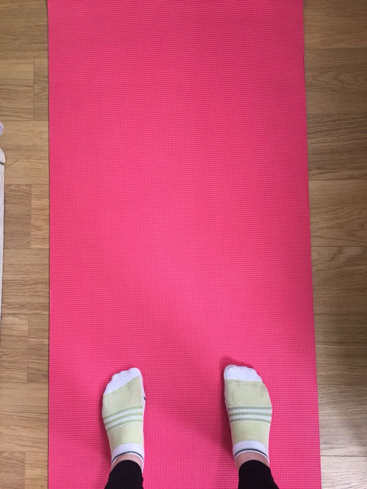 a person standing on a pink yoga mat with their feet propped up in front of them