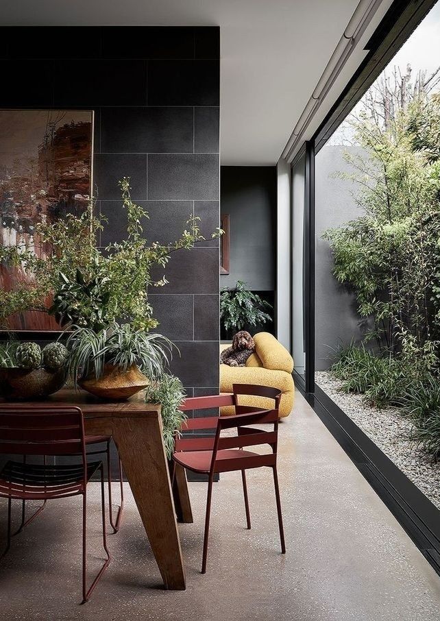 two chairs and a table in a room with plants on the wall next to it