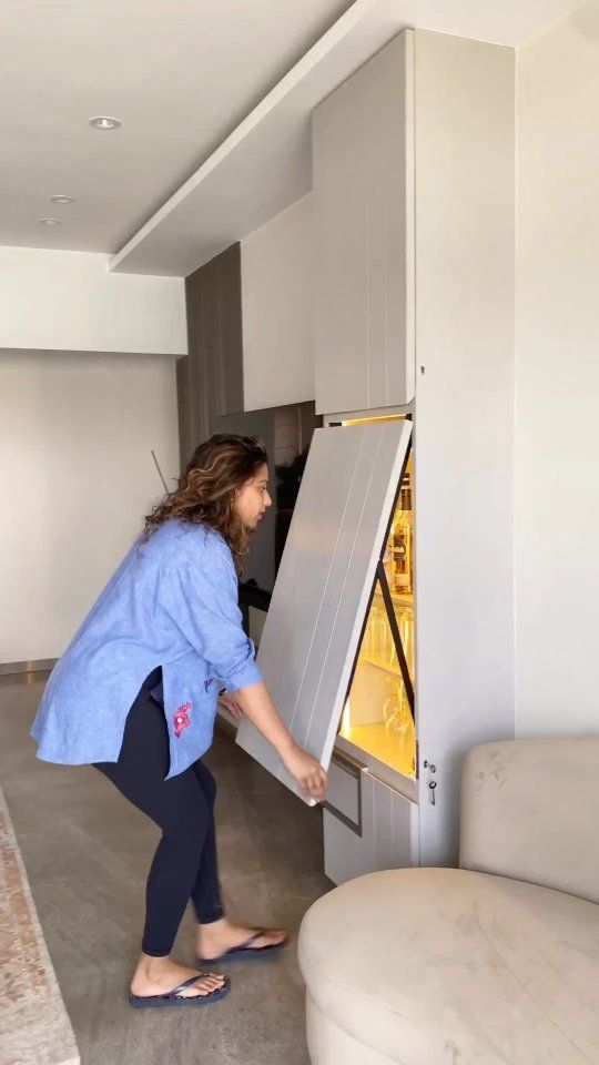 a woman is opening the refrigerator in her living room