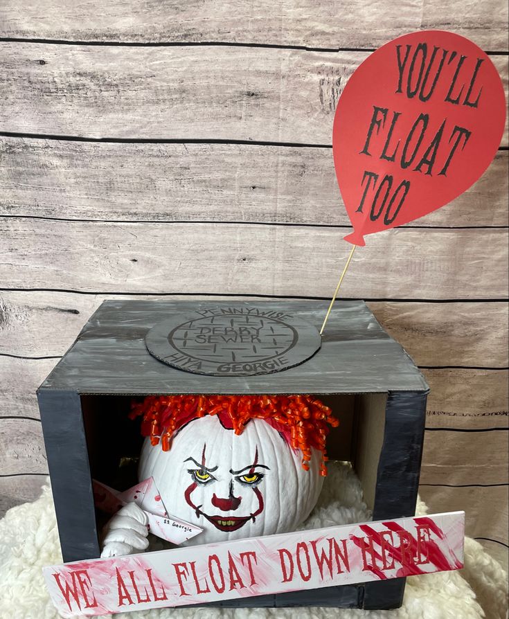 a scary looking pumpkin in a box with a sign that says you'll float too