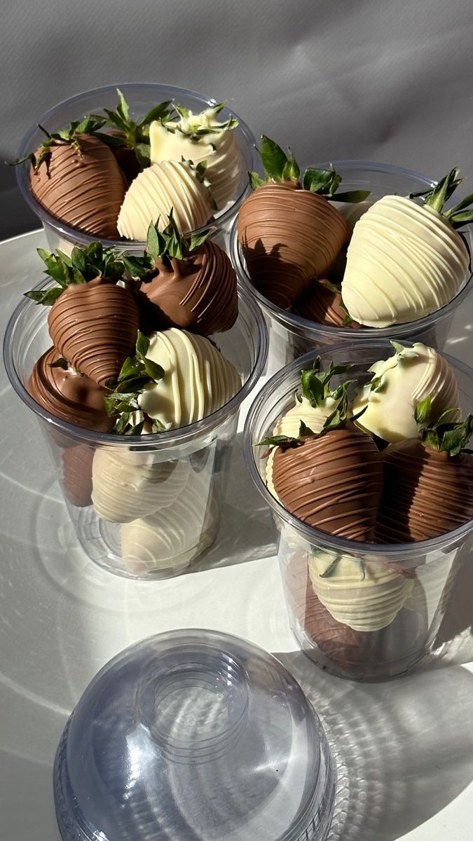 four plastic cups filled with chocolate covered strawberries