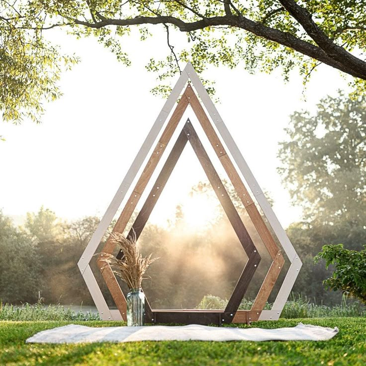 a wooden sculpture sitting on top of a lush green field next to a tree and grass covered ground