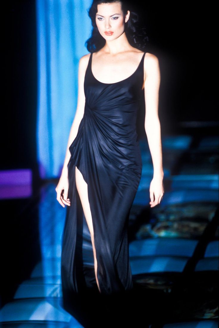 a woman walking down a runway in a black dress