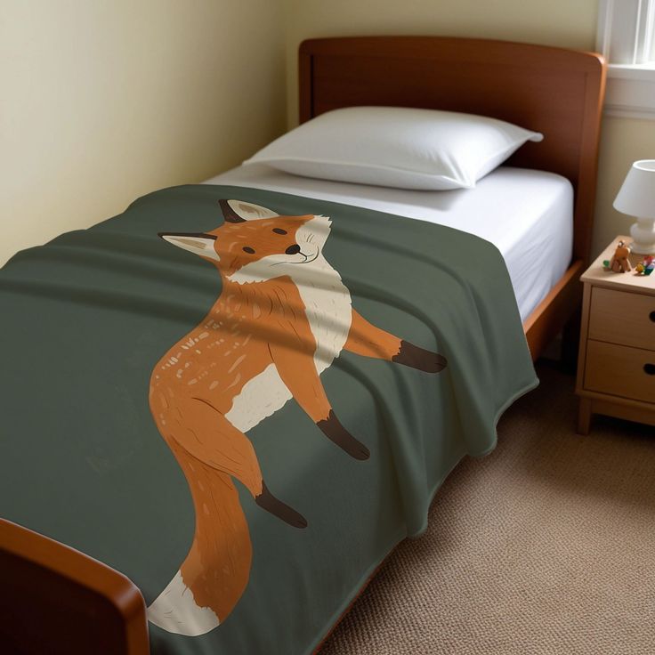 a bed with a blanket that has an image of a fox on it and is next to a night stand