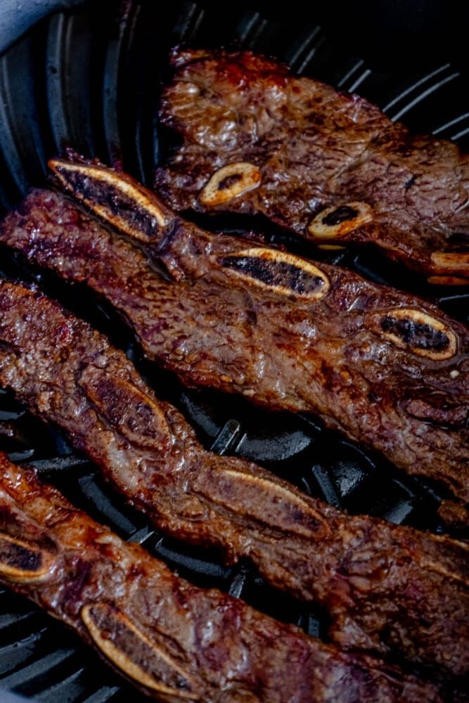 steaks are cooking on the grill in an open air fryer with sauce and seasoning