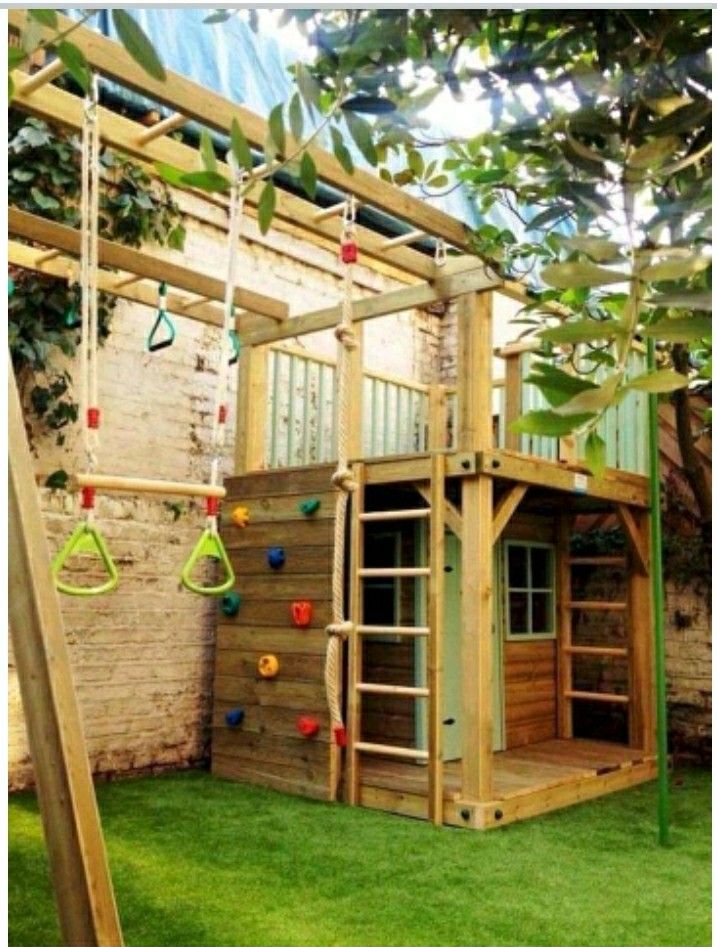 an outdoor play area with swings, climbing bars and a wooden structure in the grass