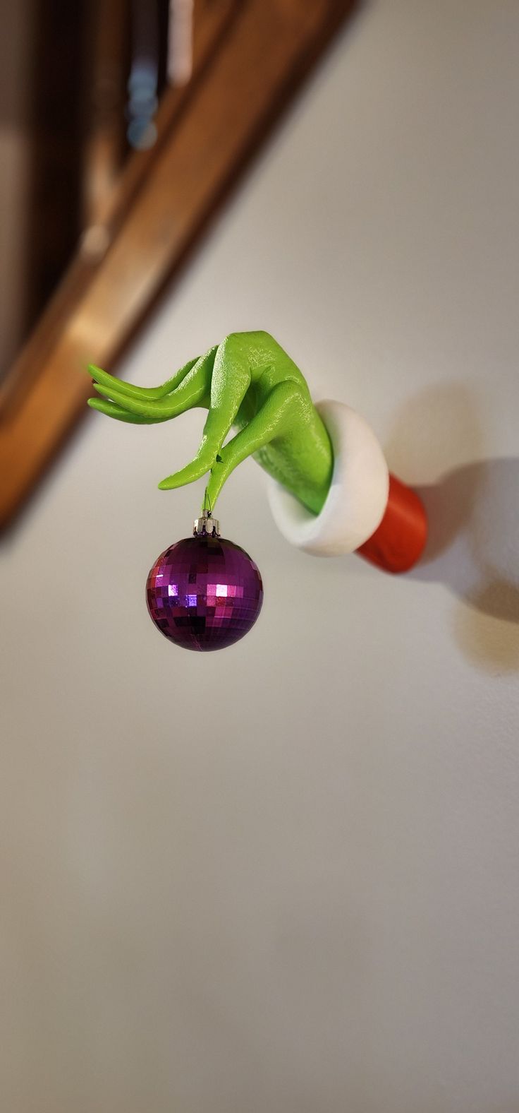 an ornament shaped like a green plant hanging from a hook on a wall