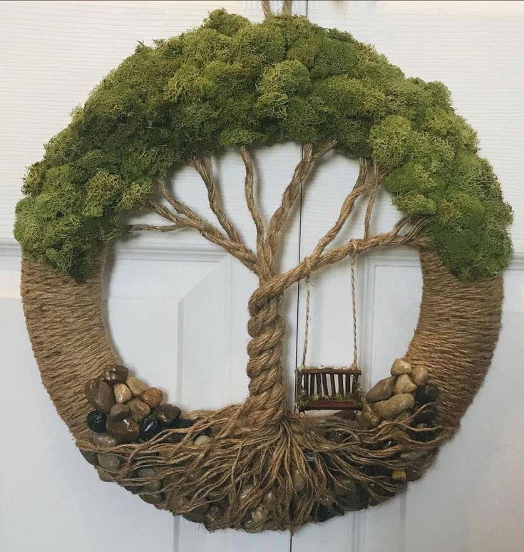 a wreath with a tree hanging on the front door, filled with rocks and plants