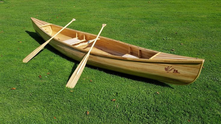 a wooden canoe with two oars on the grass