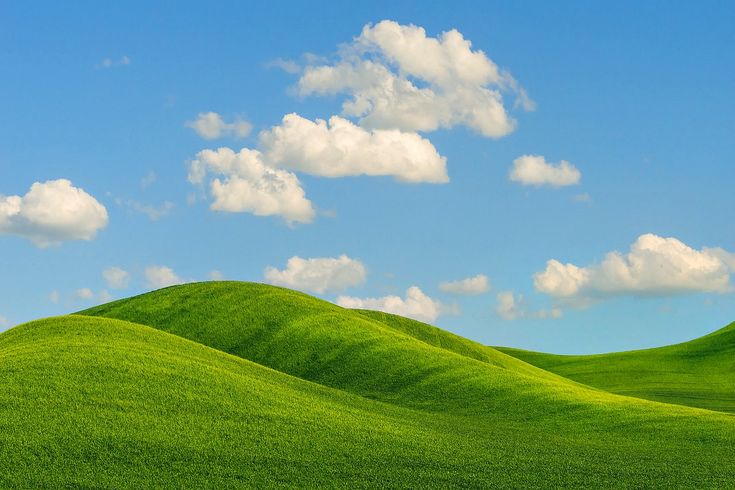 green hills under a blue sky with white clouds