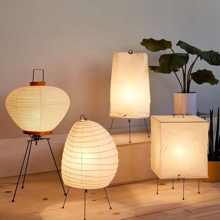 three lamps sitting on top of a wooden floor next to a plant and potted plant