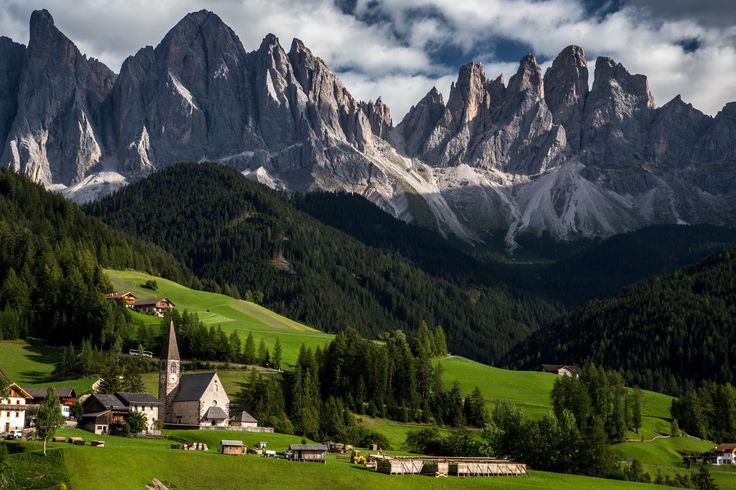 the mountains are covered in snow and green grass, with small houses on each side