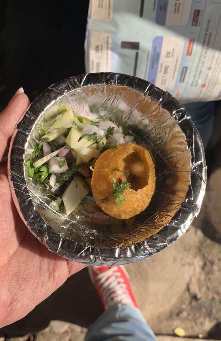 a person holding a paper plate with food in it